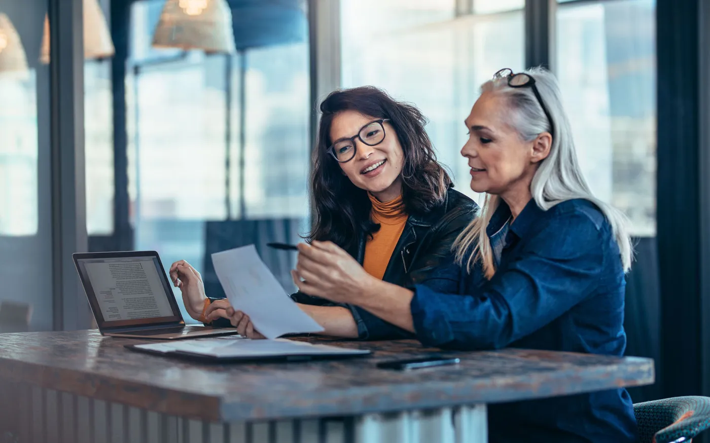 Two women analyzing documents at office