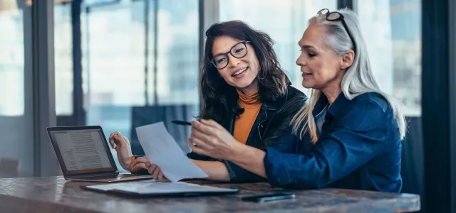 Two women analyzing documents at office